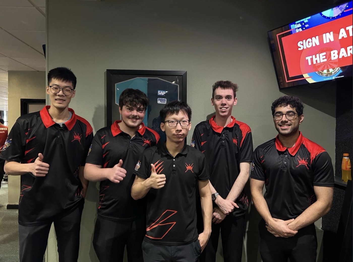 The KCL pool team at a BUCS event — five players in black and red, thumbs up.