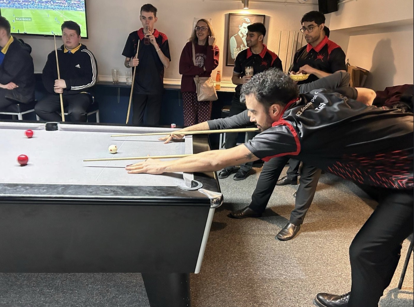 Hissan down on a shot at a Southern 8-ball match, teammates watching from behind.